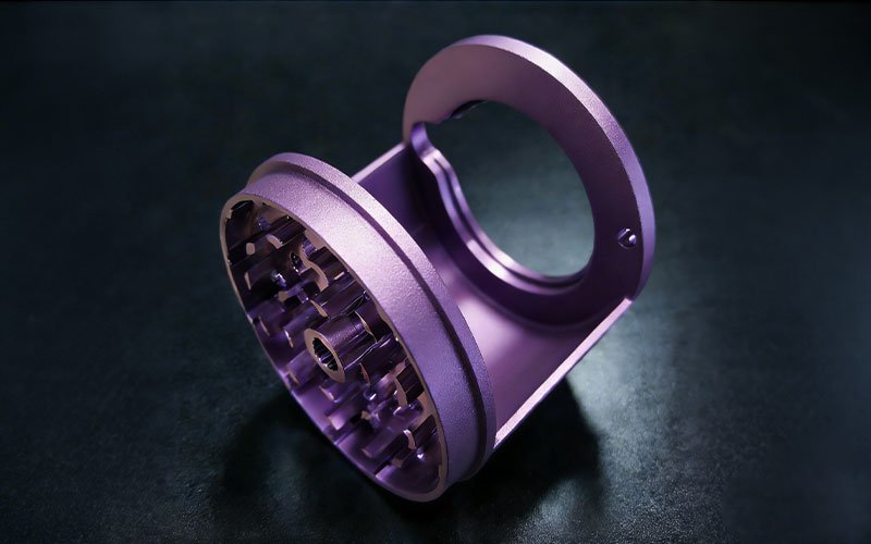 Custom CNC machined aluminum herb grinder prototype with vibrant purple anodized finish.