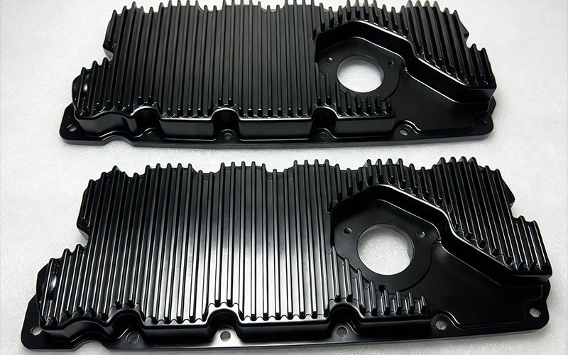 CNC machined billet aluminum oil pan with integrated cooling fins and black anodized finish.