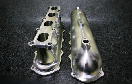 Custom billet aluminum intake manifold with CNC machined plenum and runners for high-performance engines.
