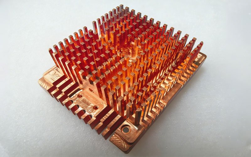 Precision CNC machined C11000 copper pin fin heatsink with complex base geometry for electronics cooling.