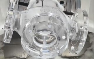 5-axis CNC machine cutting a clear high-transparency acrylic component with monocrystalline diamond (MCD) tools.
