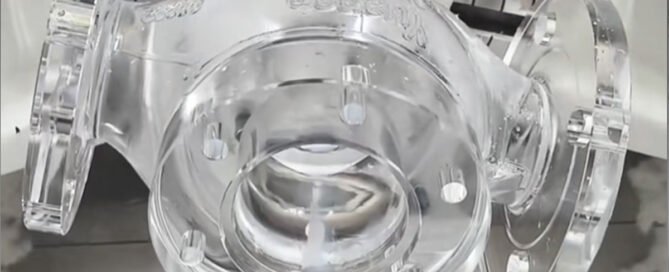 5-axis CNC machine cutting a clear high-transparency acrylic component with monocrystalline diamond (MCD) tools.