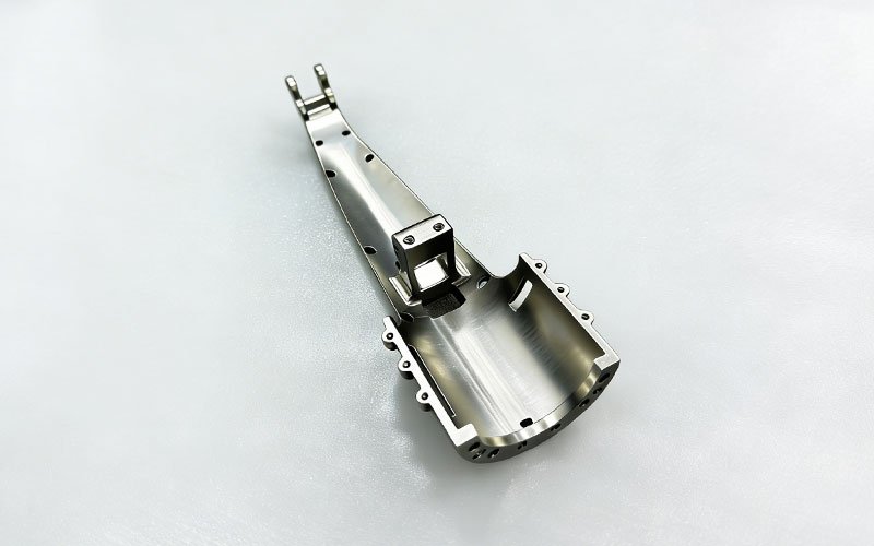 Custom CNC machined titanium structural linkage with complex 3D curved profile and internal lightweighting pockets.