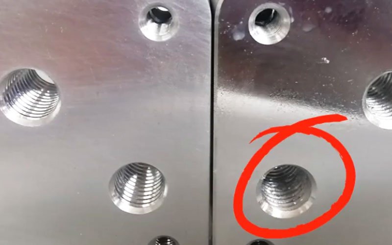 A Stripped Aluminum Threaded Hole A close-up showing a damaged and stripped threaded hole in a CNC machined aluminum part, highlighting the failure of internal threads.