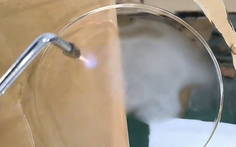 Post-Processing: Flame Polishing. Close-up of a hydrogen torch flame polishing the edge of a circular clear acrylic part to improve transparency.