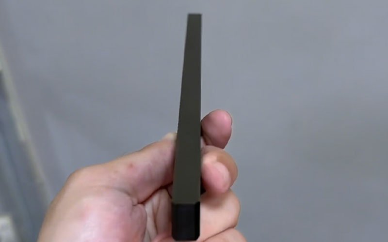Perfectly straight black POM(Delrin) part machined using custom vacuum suction fixture with deformation controlled to a minimum.