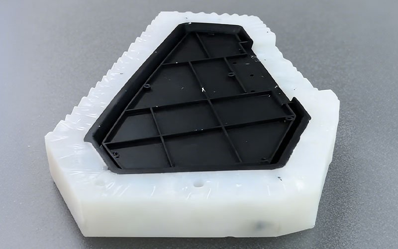 Split silicone rubber mold with a black master pattern inside, used for vacuum casting (urethane casting) prototypes.