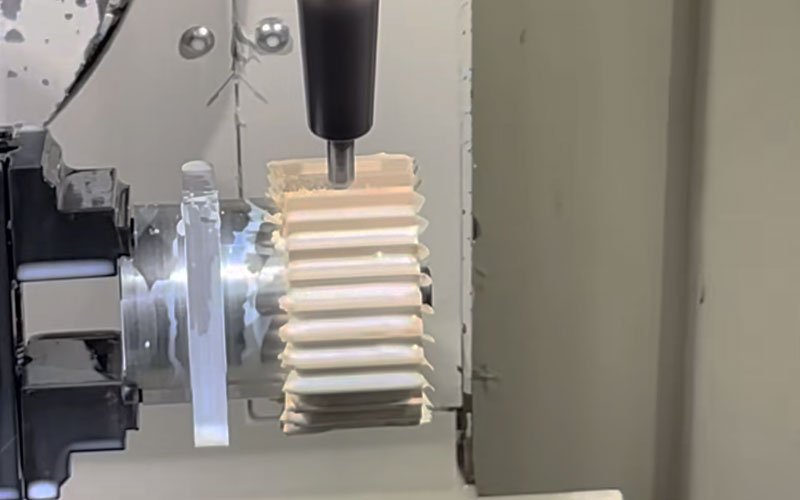 Custom CNC machining PEEK gear process. A 5-axis milling center utilizing a solid carbide end mill to generate the involute tooth profile on a turned virgin PEEK blank.
