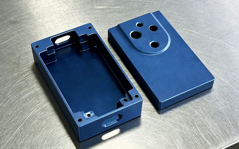 Custom CNC machined aluminum controller enclosure consisting of a deep-pocketed base and a matching cover, featuring a uniform bead-blasted blue anodized finish. 