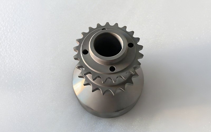 Top view of a custom CNC machined single-piece crank hub made from 15NiCr13 steel, displaying dual integral timing chain sprockets.