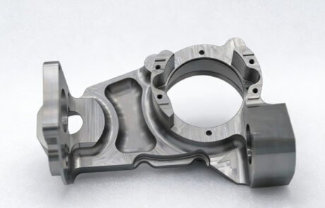 CNC machined robotic knuckle part with two perpendicular bearing bores and lightweight pocketing.