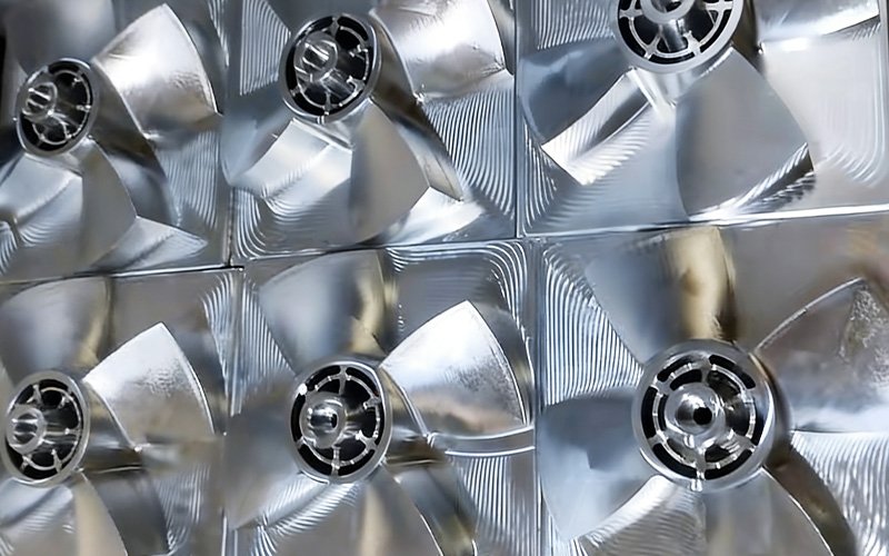 CNC machined aluminum fan blade in post-roughing stage, showing step-down marks and remaining stock before final finishing.