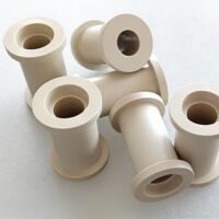 Custom CNC Machined PEEK Bushings and Sleeves Precision CNC turned natural PEEK flanged bushings and insulating sleeves, showcasing smooth surface finish and precise internal bores.