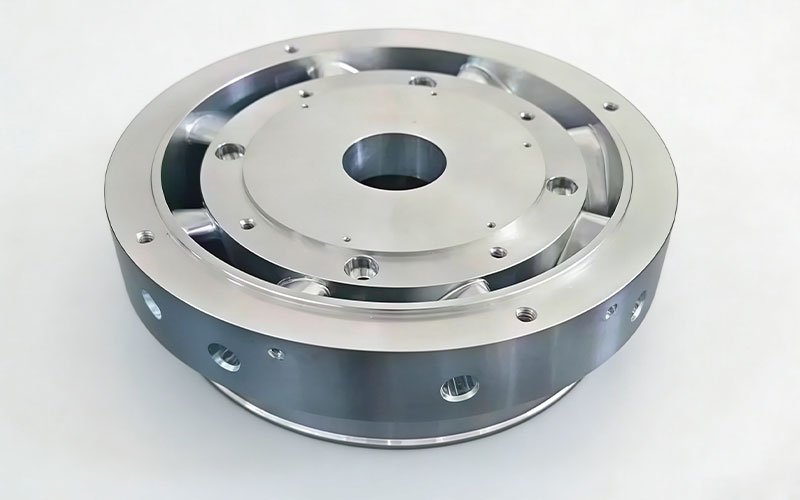 Bottom view of custom CNC milled aluminum impeller featuring integral outer shroud, precision central drive bore, and pre-machined radial dynamic balancing holes.