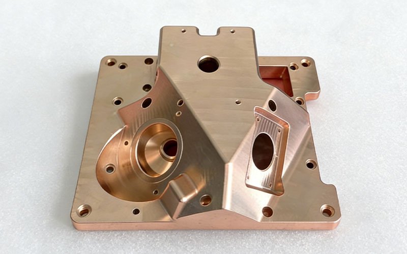 Custom CNC machined oxygen-free copper baseplate featuring multi-axis milled angled bores and precision O-ring grooves for laser cooling applications.
