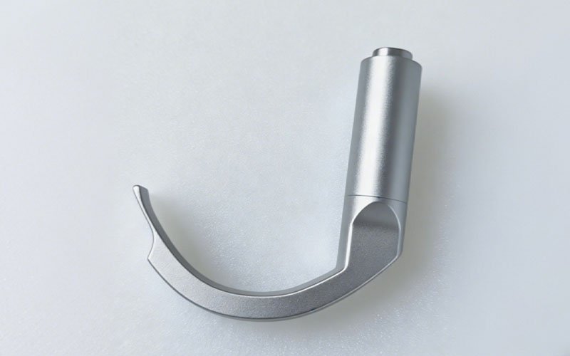 A custom 5-axis CNC machined 316L stainless steel laryngoscope blade with an anti-glare bead-blasted finish on a plain white background.