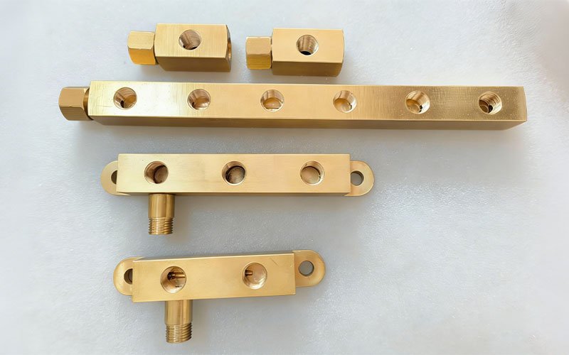 A collection of various multi-port brass manifold blocks and connectors custom-machined via CNC milling for fluid distribution systems.