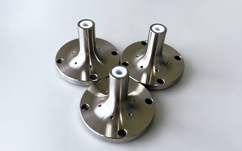 Custom CNC machined stainless steel flange parts with polished finish, tapered neck, and central insulating liner, manufactured via turning and milling.