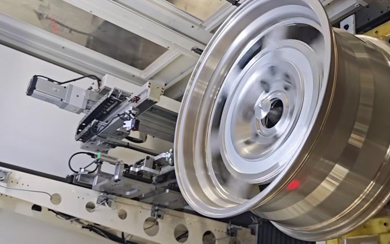 A custom CNC machined aluminum wheel spinning on an automated testing machine to measure precise dynamic balance and geometric runout.