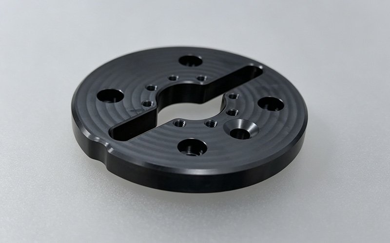 PEEK GF30 CNC Machining — Precision Flange Disc CNC machined PEEK GF30 flange disc with S-profile slot and radial hole pattern