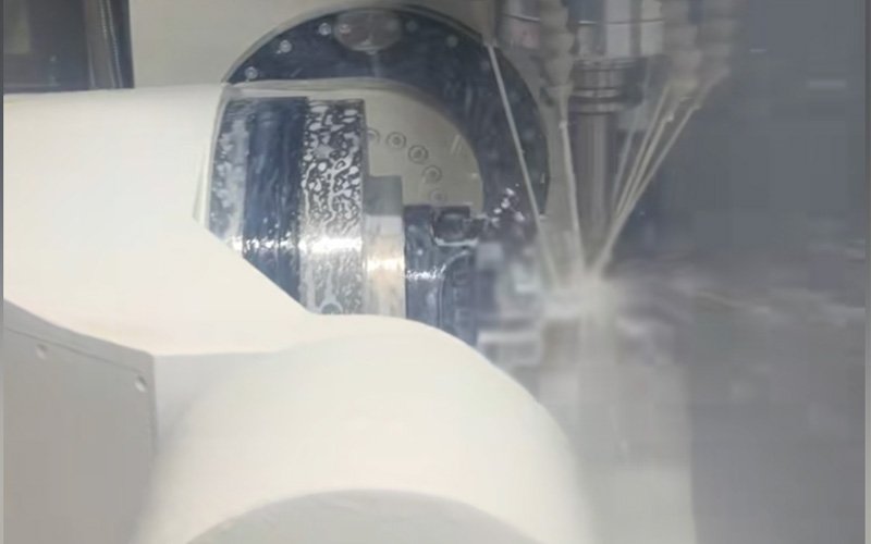 5-axis CNC milling machine cutting custom 316L stainless steel housing with coolant spray