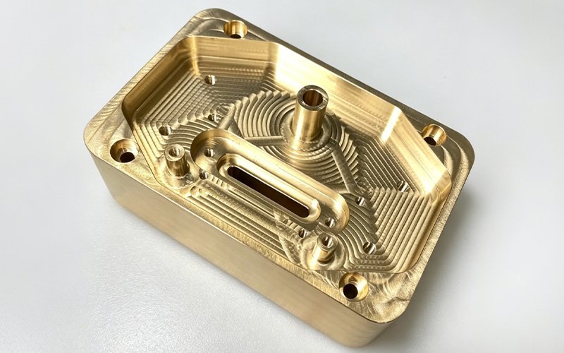 Custom CNC milled brass part with deep rectangular cavity and multiple internal features for electronics and electrical equipment