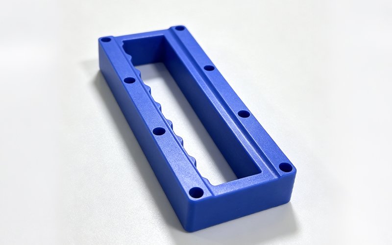 Blue Delrin CNC machining case — custom frame part with scalloped inner profile and countersunk holes
