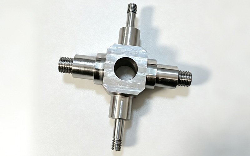 Custom cross shaft in stainless steel with four stepped threaded arms at 90 degrees and center through bore, machined to print