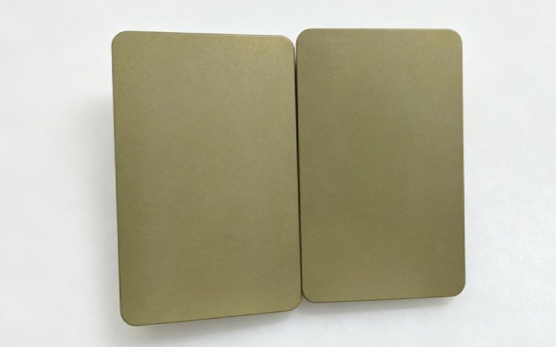 Two hard-anodized 7075 aluminum plates where the dye shifted to an uneven olive-khaki color