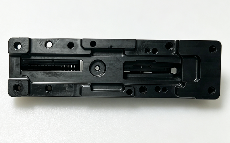 CNC machined black PEEK base plate for automation equipment with precision guide slots, central boss and mounting holes