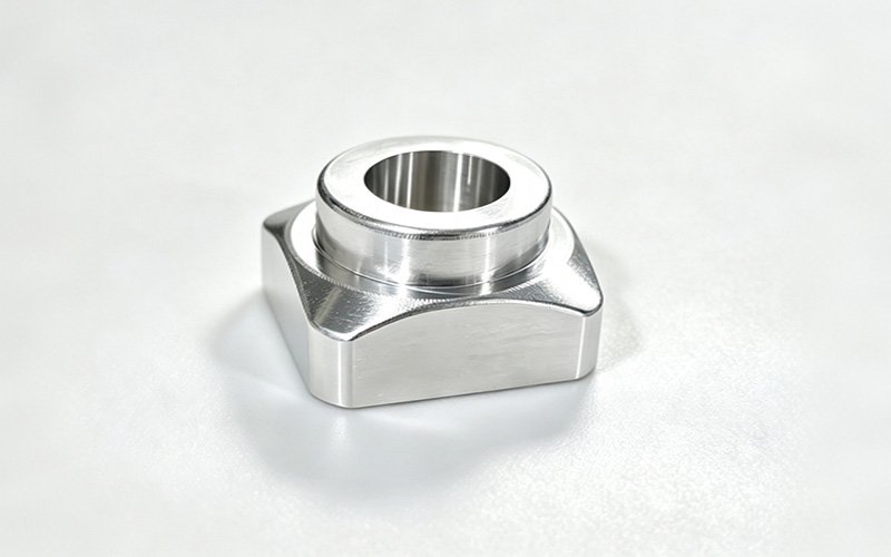Custom CNC machined 7075 aluminum action camera housing with a square base and stepped precision bore, as-machined finish