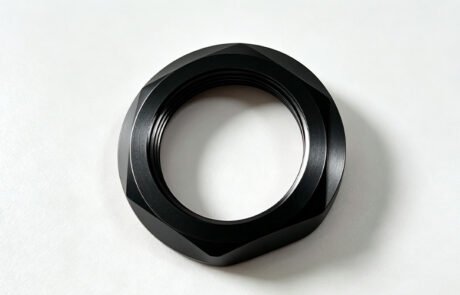 Custom CNC machined anti-slip lock nut in black anodized aluminum with faceted grip profile and anti-slip face teeth