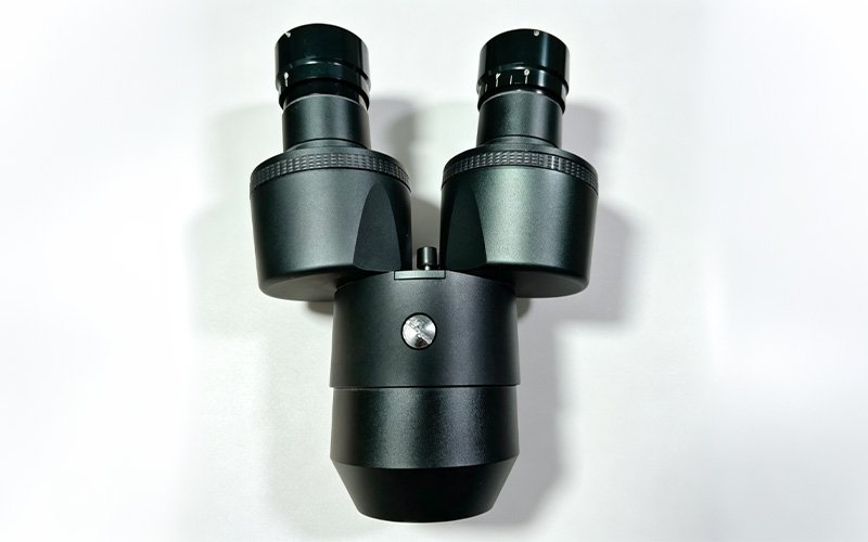 Custom CNC machined aluminum microscope housing for a binocular head, black anodized with eyepiece tubes and knurled rings