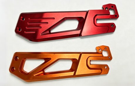 Custom CNC machined billet aluminum motorcycle swingarms in red and orange anodized finishes