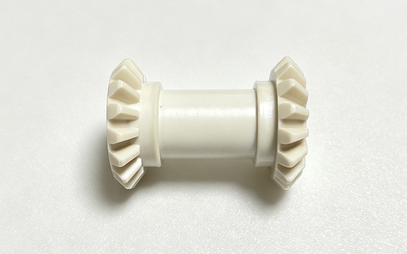 Side view of a custom CNC machined PEEK double bevel gear with two bevel gears on one shaft