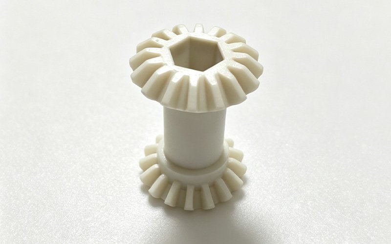Custom PEEK Double Bevel Gear Custom CNC machined natural PEEK double bevel gear with two bevel gears on one shaft and a hexagonal bore