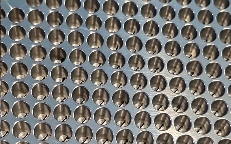 Close-up of counterbored holes and laser-cut slits on a custom spinneret plate
