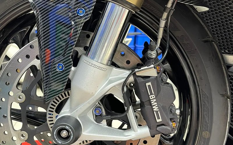 Blue anodized titanium bolts on a motorcycle front brake caliper