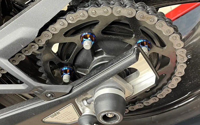 Blue titanium bolts on a motorcycle rear sprocket carrier