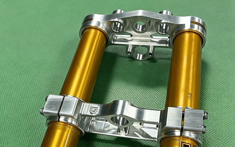 Custom triple clamp assembled with the front fork tubes, forming the complete front-end assembly